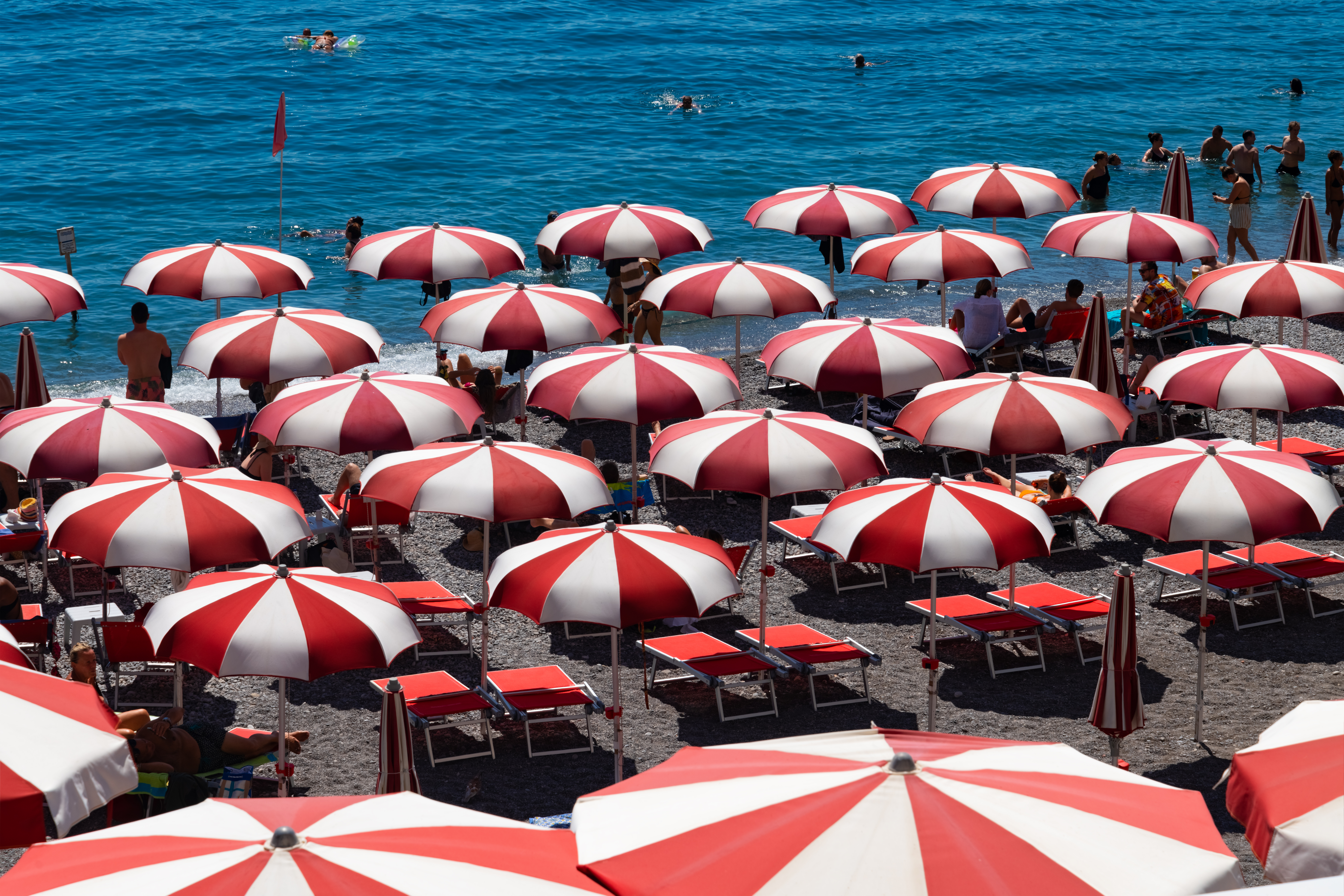 Amalfi beach on famous Amalfi Coast Italy. Rows of red and white parasols or beach umbrellas.