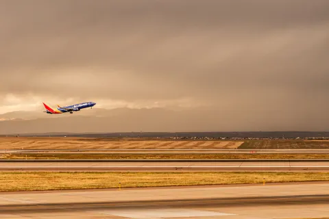 A Southwest Airlines Commercial Passenger Jet Takes off and climbs to altitude with grey storm clouds in the background 