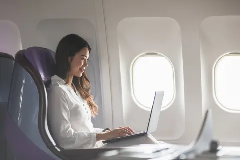 oung woman using laptop sitting near windows at first class on airplane during flight