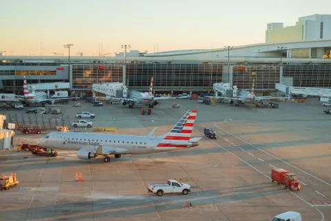 American airlines plane parking during sunset in a busy DFW International airport