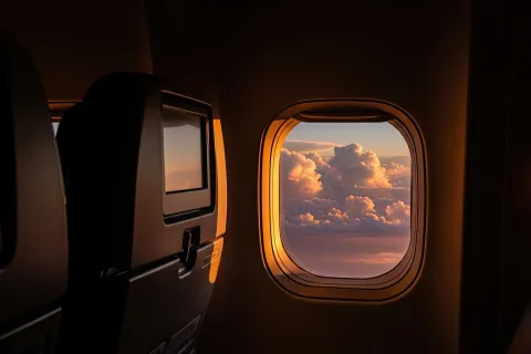 Interior airplane view of window with sunset clouds and seats