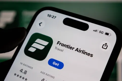 Closeup of a smartphone screen displaying the frontier airlines mobile app in the apple app store, showcasing the logo and download button