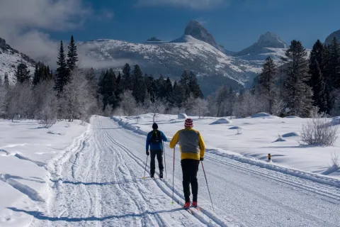 Two men classic Nordic skiing in Teton Canyon near Driggs Idaho and Alta, Wyoming, Grand Teton in distance
