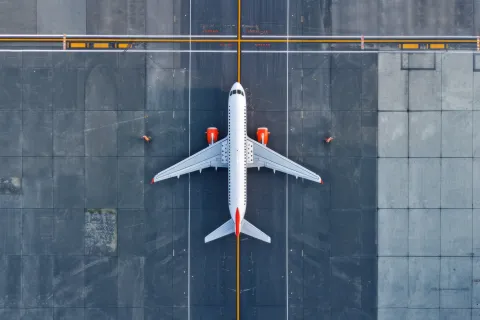 Top down view on commercial airplane docking in terminal in the parking lot of the airport apron, waiting for services maintenance, refilling fuel services after airspace lock down