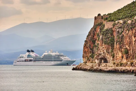 Seabourn Encore cruise ship anchored in the Argolic Gulf near the cliffside Arvanitia path and Palamidi fortress walls, Nafplio, Peloponnese, Greece, Europe.