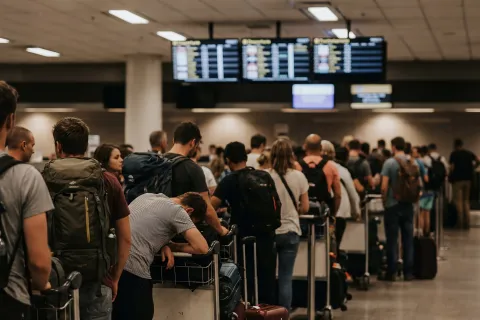 Passengers waiting in long airport check-in queue for flight departure at terminal