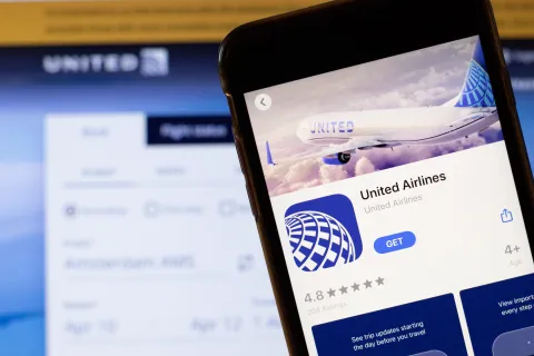 United Airlines app logo on phone screen close up with website on background with icon