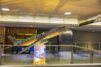  Decorative model of American Airlines airplane with colorful artwork on display inside JFK Airport terminal in New York.