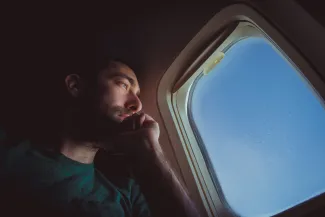 man looking out of airplane window pondering the meaning of life