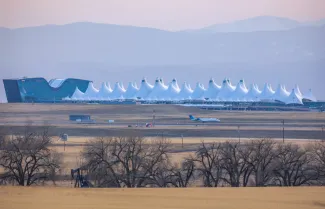 Agricultural landscape with naked spring trees and oil pump in the prairie of Eastern Colorado. The Denver International Airport