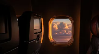 Interior airplane view of window with sunset clouds and seats