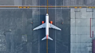 Top down view on commercial airplane docking in terminal in the parking lot of the airport apron, waiting for services maintenance, refilling fuel services after airspace lock down