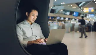 Asian man working on laptop in airport lounge