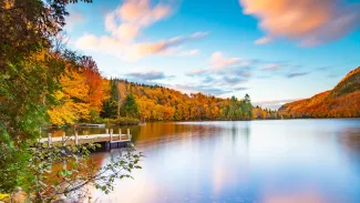 Lac-du-missionaire, Canada: Morning fog on the lake of Lac-du-missionaire with colorful leaves in Quebec in a sunny autumn day