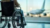 man sitting in wheelchair looking through window at airplane on the tarmac