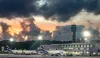 LATAM Airbus A320 parked at gate at Salvador Bahia Airport with the air traffic control tower in the background at dawn