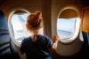 Adorable little girl traveling by an airplane. Child sitting by aircraft window and looking outside. Traveling with kids abroad. Family on summer