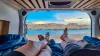 Legs of couple lying in camper van with panoramic sunset view of Wahweap Bay at Lake Powell, Glen Canyon