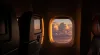 Interior airplane view of window with sunset clouds and seats