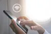 Woman hand using smartphone with wifi icon in airplane background.