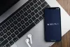 Delta Airlines app on the smartphone screen on wooden background with a computer beside it.