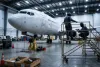 airliner nose on jacks maintenance hangar technicians on scaffold 737 deep aircraft on wide view