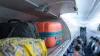 Carry-on luggage in an airplane overhead bin with suitcases and travel bags during boarding