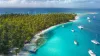 San Blas Islands, Panama - Drone Aerial View of many Sailboats & Sailing Yachts anchored in turquoise Water of Blue Lagoon next to white Sand Beach of Tropical Caribbean Island with green Palm Trees. 