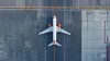 Top down view on commercial airplane docking in terminal in the parking lot of the airport apron, waiting for services maintenance, refilling fuel services after airspace lock down