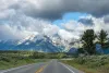 Scenic road approaching the Mount Moran Turnout with dramatic clouds surrounding the snowcapped Teton Range in Grand Teton National Park, Wyoming, USA