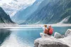 Travelers couple look at the mountain lake. Travel and active life concept with team. Adventure and travel in the mountains region in the Austria